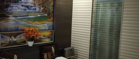 Une chambre d’hôtel avec un lit, un tableau représentant une cascade et une fenêtre avec des stores.