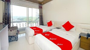 A hotel room with two beds, a balcony, and a view of the outdoors. - Hotel brijwasi palace (Yamkeshwar)