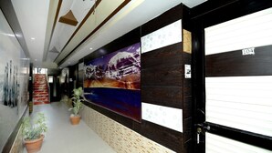 A hallway with a wooden wall, a large painting, and a door with a number sign. - Hotel brijwasi palace (Yamkeshwar)