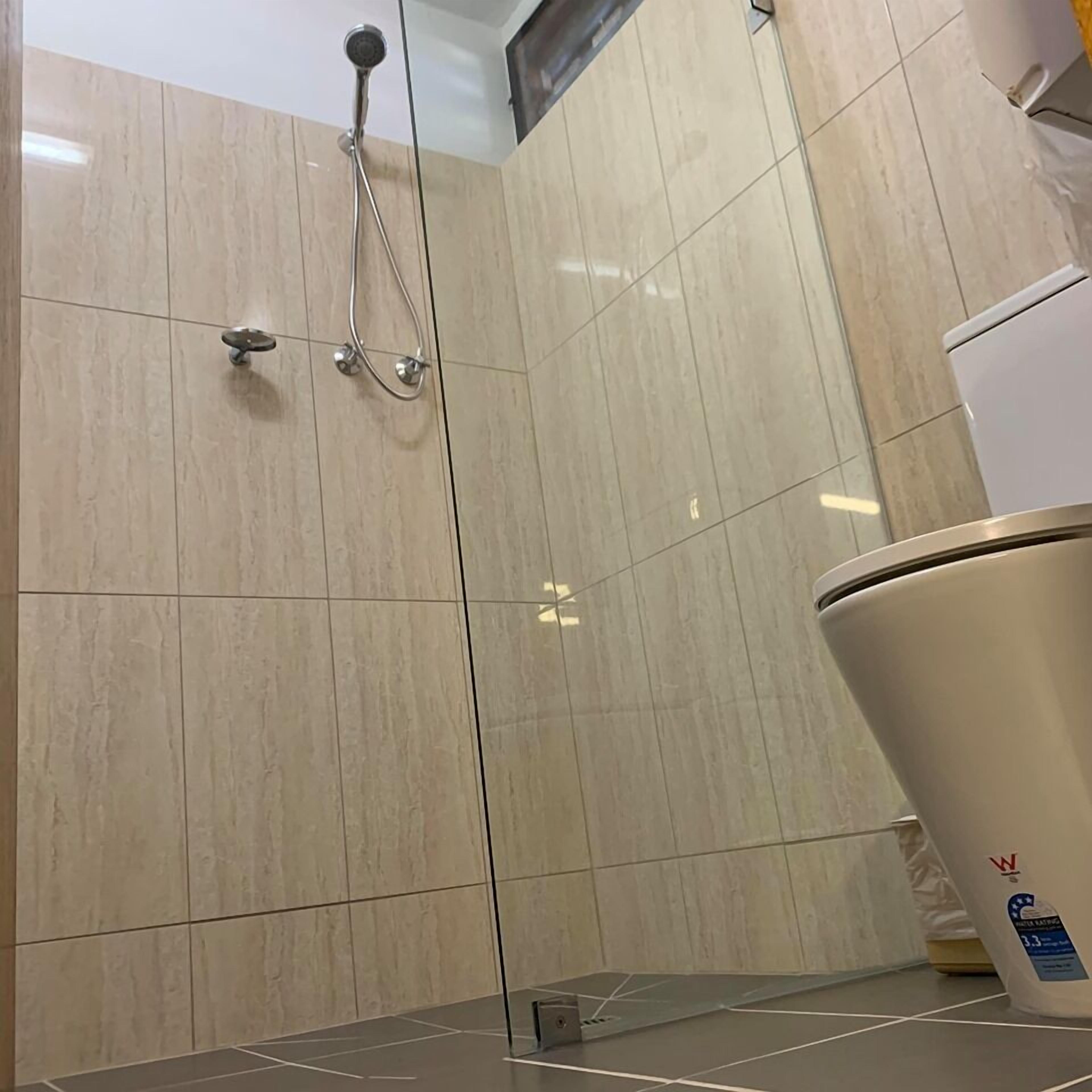 Un baño con ducha, paredes de azulejos y un inodoro.