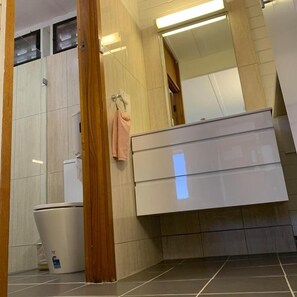 Ein modernes Badezimmer mit Toilette, Waschbecken und Spiegel.