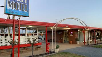 Un motel Finley con fachada roja, cerca de un cerco blanco y un letrero que dice 'By the Lake'.