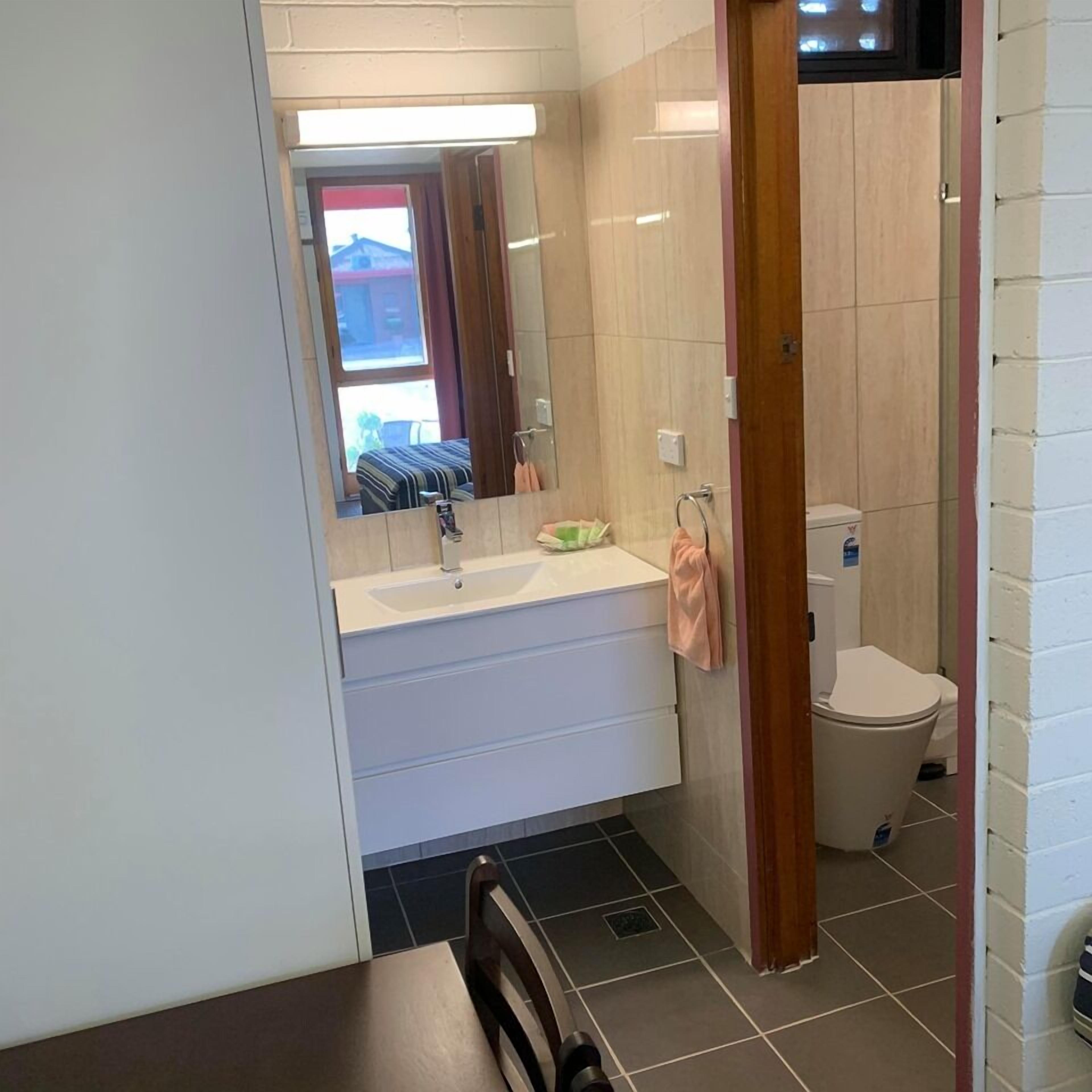 A small bathroom with a sink, mirror, and toilet.