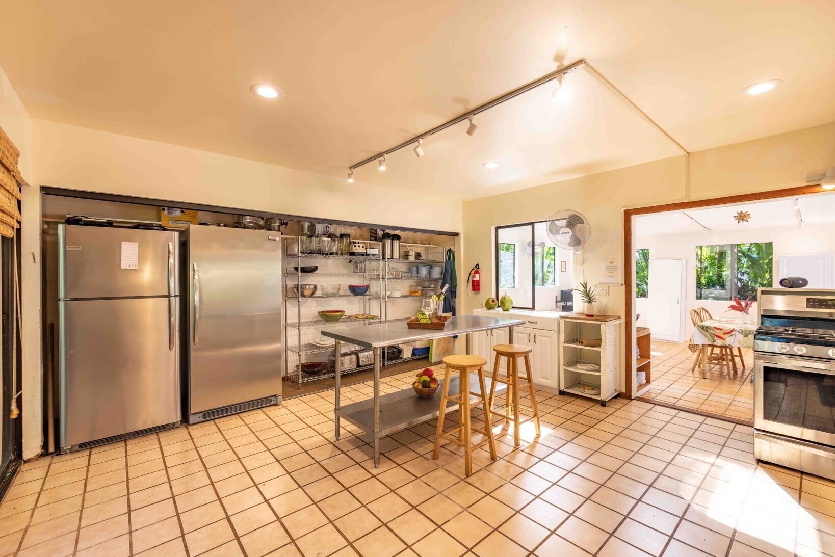 A spacious kitchen with stainless steel appliances, a tiled floor, and a large window providing natural light.