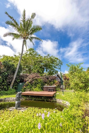 A serene garden with a palm tree, a hot tub, and a statue.