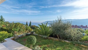 A landscaped garden with a variety of plants and a view of distant mountains and a body of water. - Nice studio in Rabac with house sea view (Rabac)