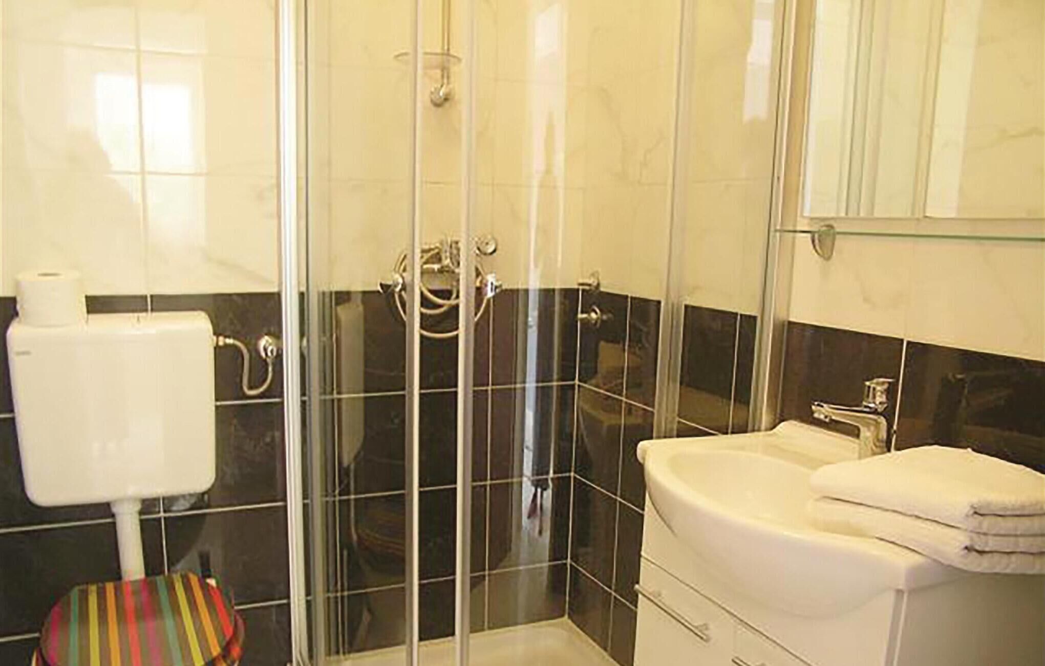 Une salle de bain avec une douche à parois de verre, des toilettes et un lavabo avec un miroir au-dessus.