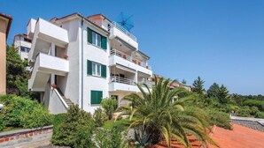 A multi-story residential building with balconies, a staircase, and a garden with palm trees. - Nice studio in Rabac with house sea view (Rabac)
