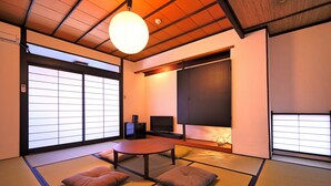 A traditional Japanese room with tatami flooring, a low table, cushions, sliding doors, and a television. - Setouchi Mangetsusou (Takamatsu)