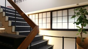 A staircase with a wooden handrail, a potted plant, and a traditional sliding door in the background. - Setouchi Mangetsusou (Takamatsu)