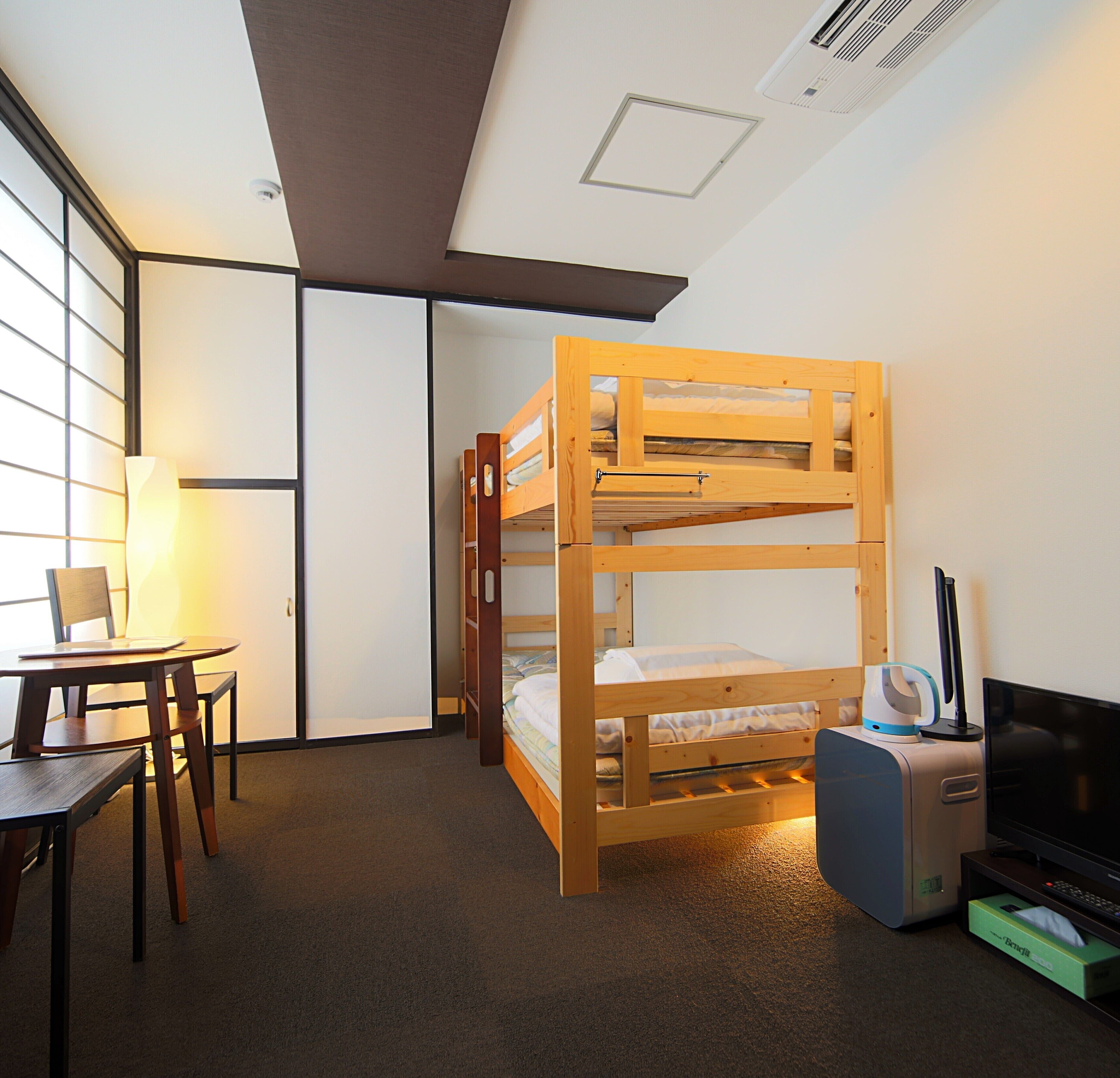 A room with a bunk bed, a desk with a chair, a television, and a lamp.