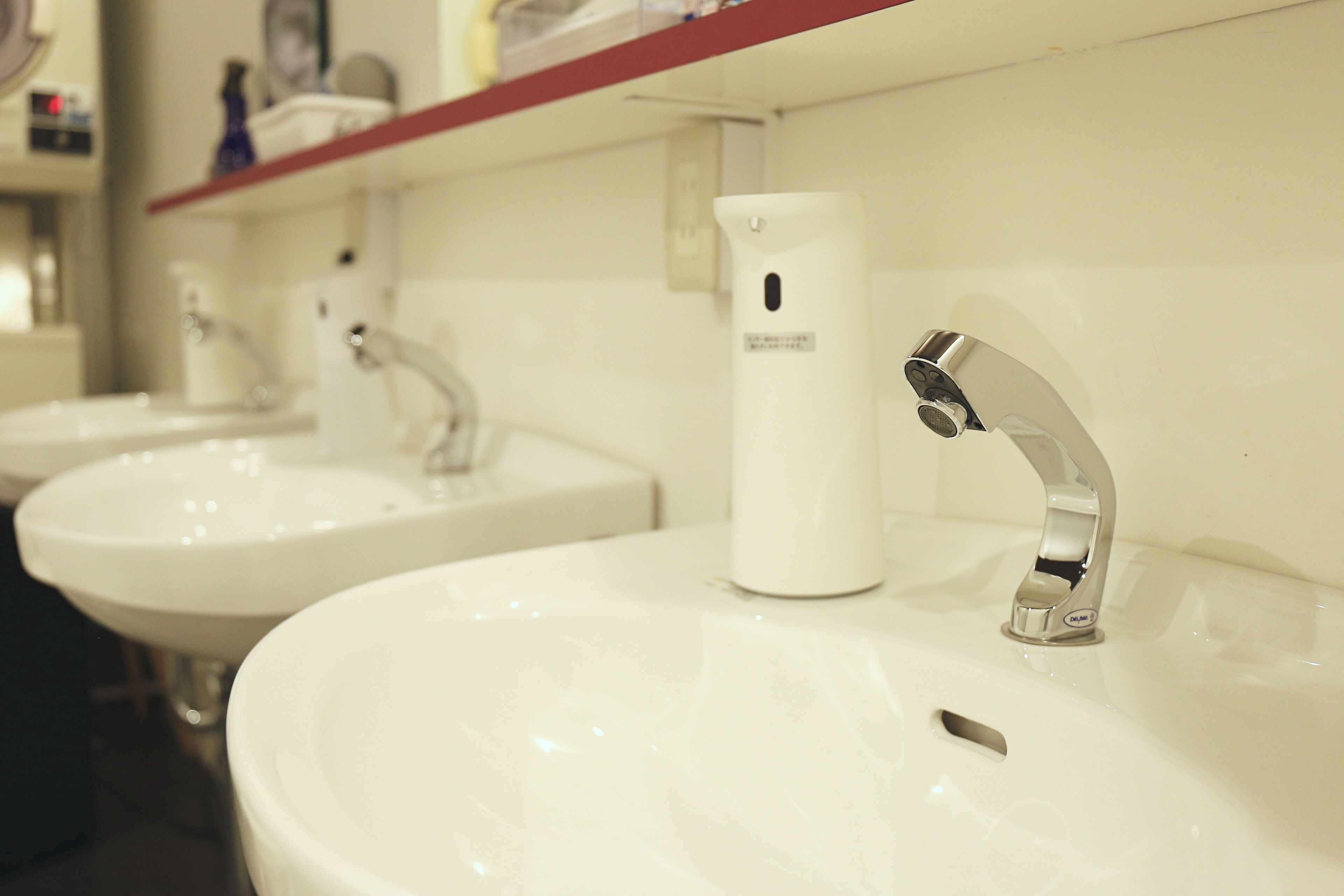 A row of white sinks with chrome faucets in a restroom.