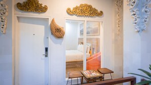 Una habitación con cama, una mesita pequeña, un banco y decoración en la pared.