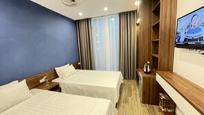 A hotel room with two beds, a TV on the wall, a wooden shelf, and a window with curtains. - Thanh Nam Hotel (Cua Lo)