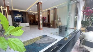 A hotel lobby with a reception desk, seating area, and a glass partition. - Thanh Nam Hotel (Cua Lo)