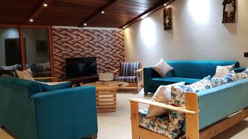 Una sala de estar acogedora con sofás color aguamarina, una mesa de centro de madera y un televisor.