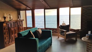 A room with a view of the sea, a wooden ceiling, a green sofa, a wooden chair, and a small table with a glass. - Apartment near Lady of the Sea & Phoenician Wall (Batroun)