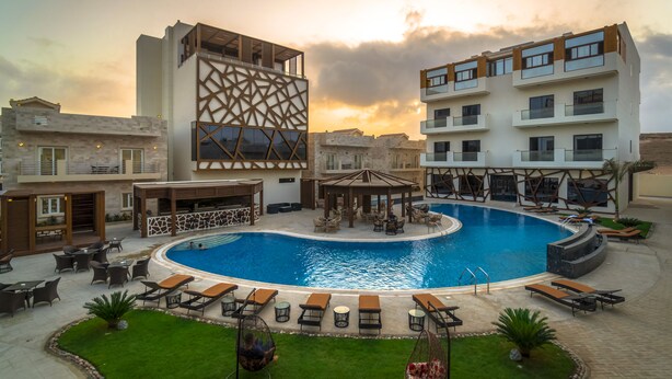 Un hotel moderno con piscina, mobiliario exterior y un diseño arquitectónico único.