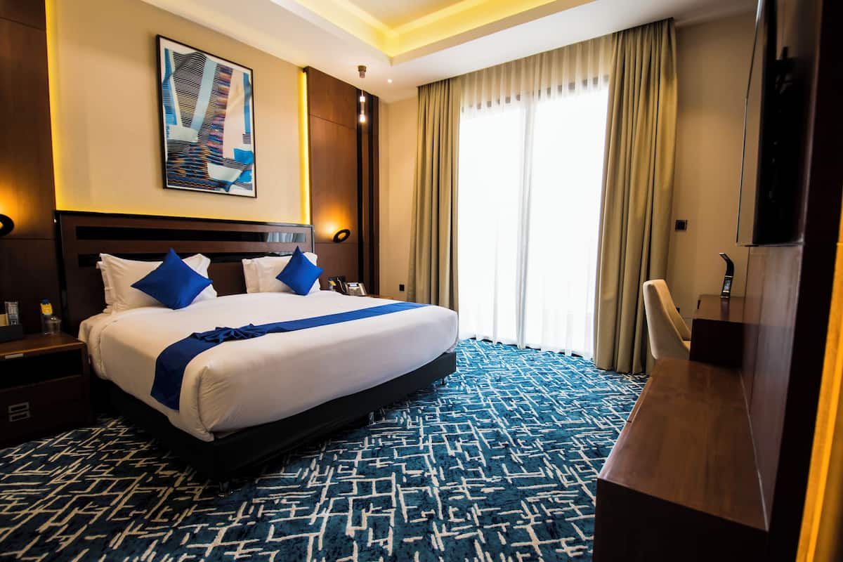 Una habitación de hotel con una cama grande, un escritorio, un televisor y un cuadro en la pared.