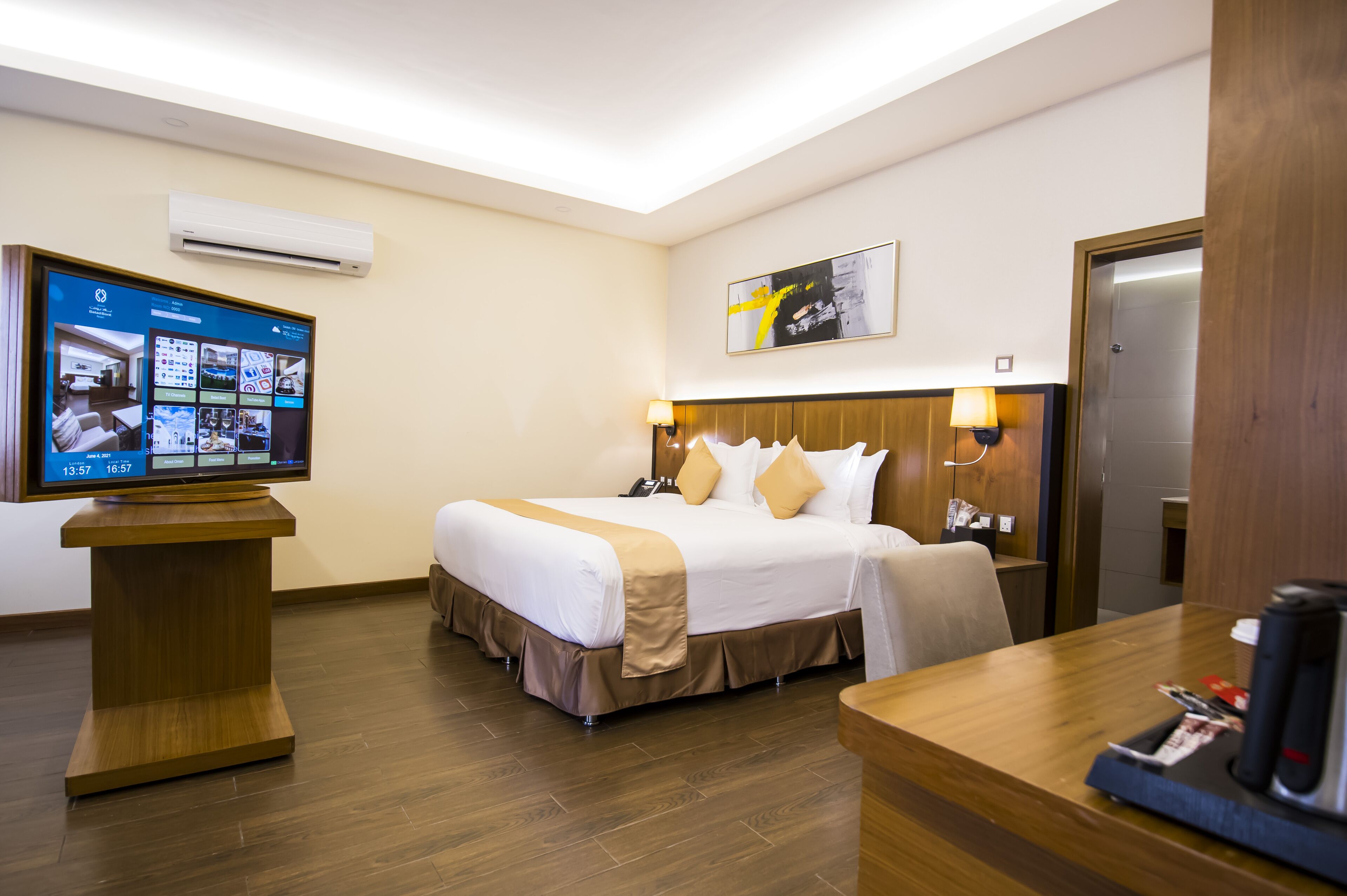 Una habitación de hotel con cama, mesita de noche, televisión y un escritorio de madera.
