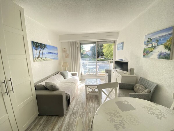 A compact living space with a sofa, a dining table, and a TV. - Beautiful 2 rooms Moulleau center with parking (ARCACHON)