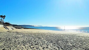 Ein Strand mit blauem Himmel, sandigem Ufer und weiter Meerblick.