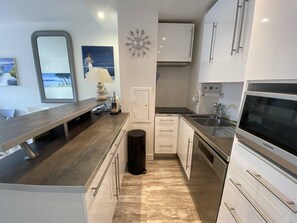 A modern kitchen with a built-in oven, stainless steel appliances, and a large window overlooking the sea. - Beautiful 2 rooms Moulleau center with parking (ARCACHON)