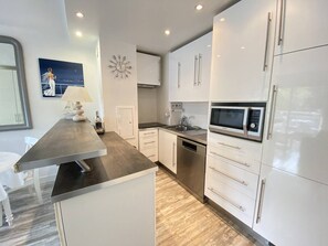 A modern kitchen with white cabinets, a stainless steel countertop, and a built-in microwave.