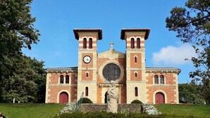 Eine Kirche mit zwei Türmen, einem großen Rundfenster und einer Statue im Vorbereich.
