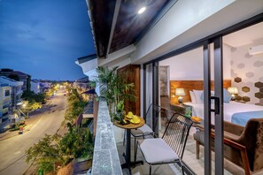 A balcony with a table, chairs, and a view of a street at dusk. - Square Villa Hoi An (Da Nang)