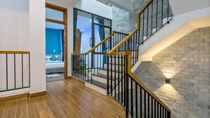 Un interior moderno con piso de madera, una escalera con barandillas negras y una pared de ladrillo.