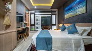 A hotel room with a bed, desk, chair, and a view of the outside.