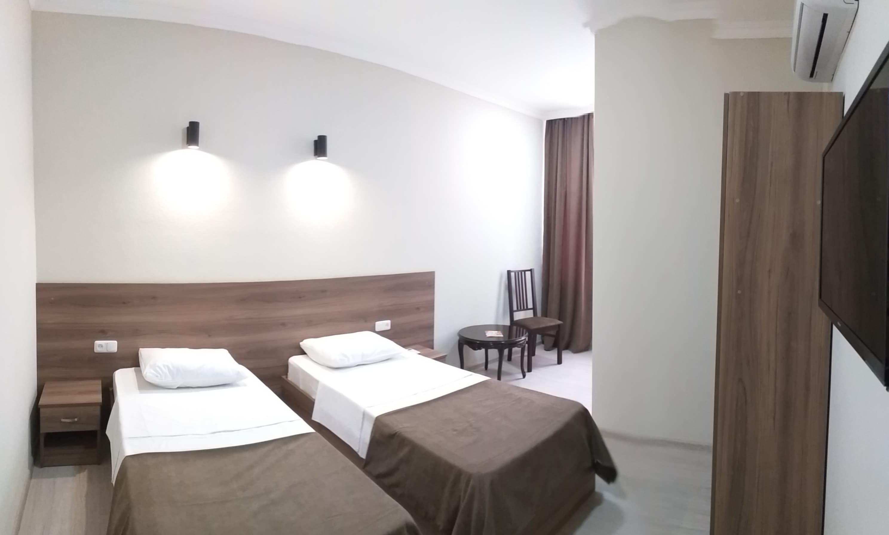 Una habitación de hotel con dos camas, una mesita, una silla y un televisor.