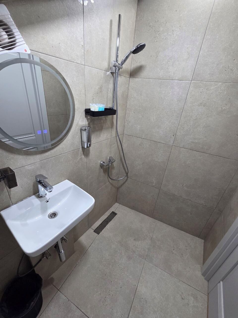 Ein Badezimmer mit Waschbecken, Spiegel, Dusche und gefliesten Wänden.
