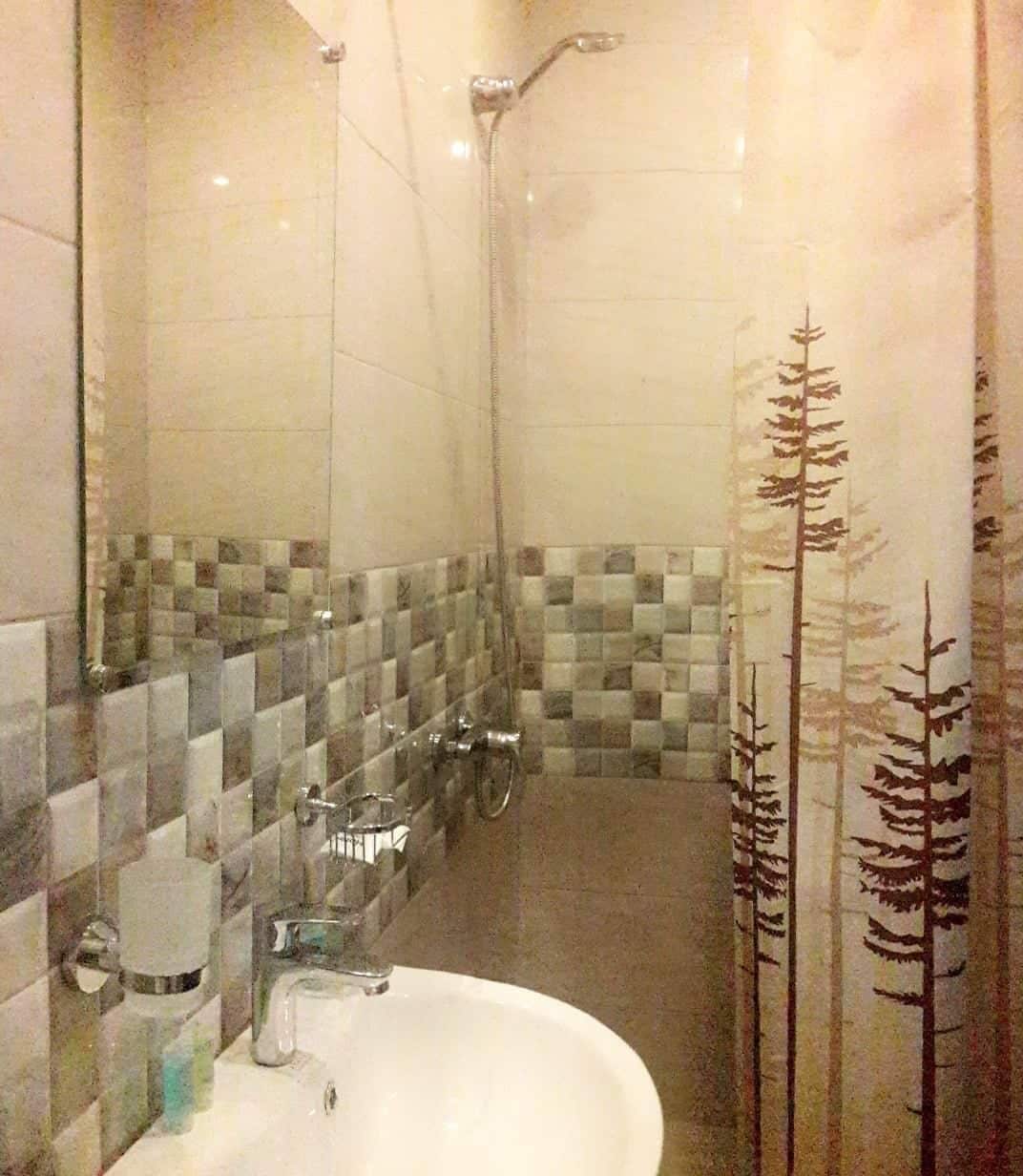 A bathroom with a tiled shower, a sink, and a mirror.