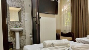 Una habitación de hotel con cama, televisor montado en la pared, lavamanos y espejo.