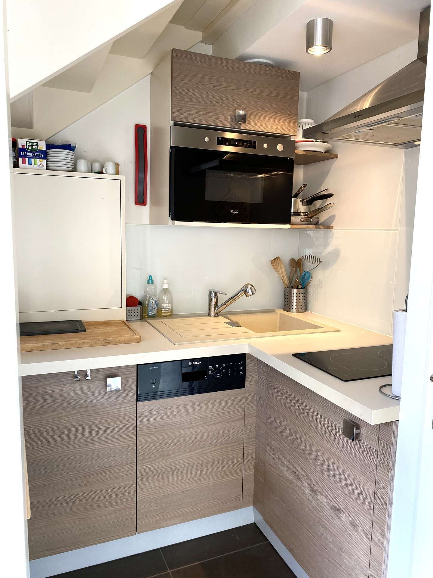 A compact kitchen with a dishwasher, oven, and a built-in microwave.