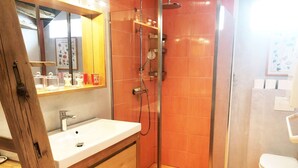 Ein Badezimmer mit Holzwaschtisch, einer Duschkabine aus Glas und einer weißen Toilette.