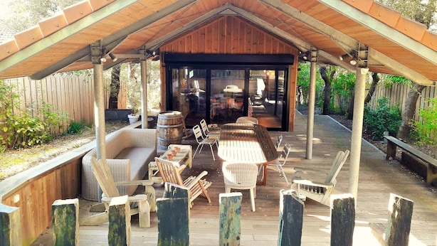 Eine überdachte Terrasse im Freien mit Holzmöbeln und Blick auf den Garten.