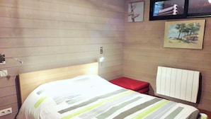 Ein Hotelzimmer mit einem Bett, einer roten Bank, einem Wandradiator und einem Gemälde.