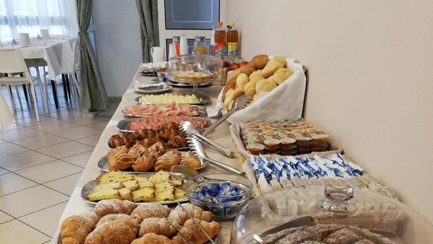 Uma mesa de buffet com diversos doces e pastéis, incluindo tortas, bolos e pão.