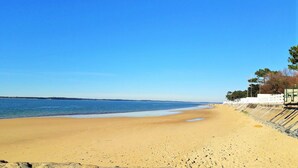 Une vaste plage de sable fin, sous un ciel bleu dégagé et une mer calme.