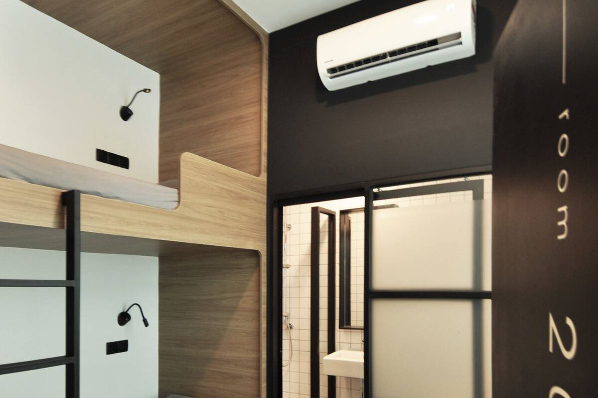 A compact room with bunk beds, a modern air conditioning unit, and a visible bathroom door.