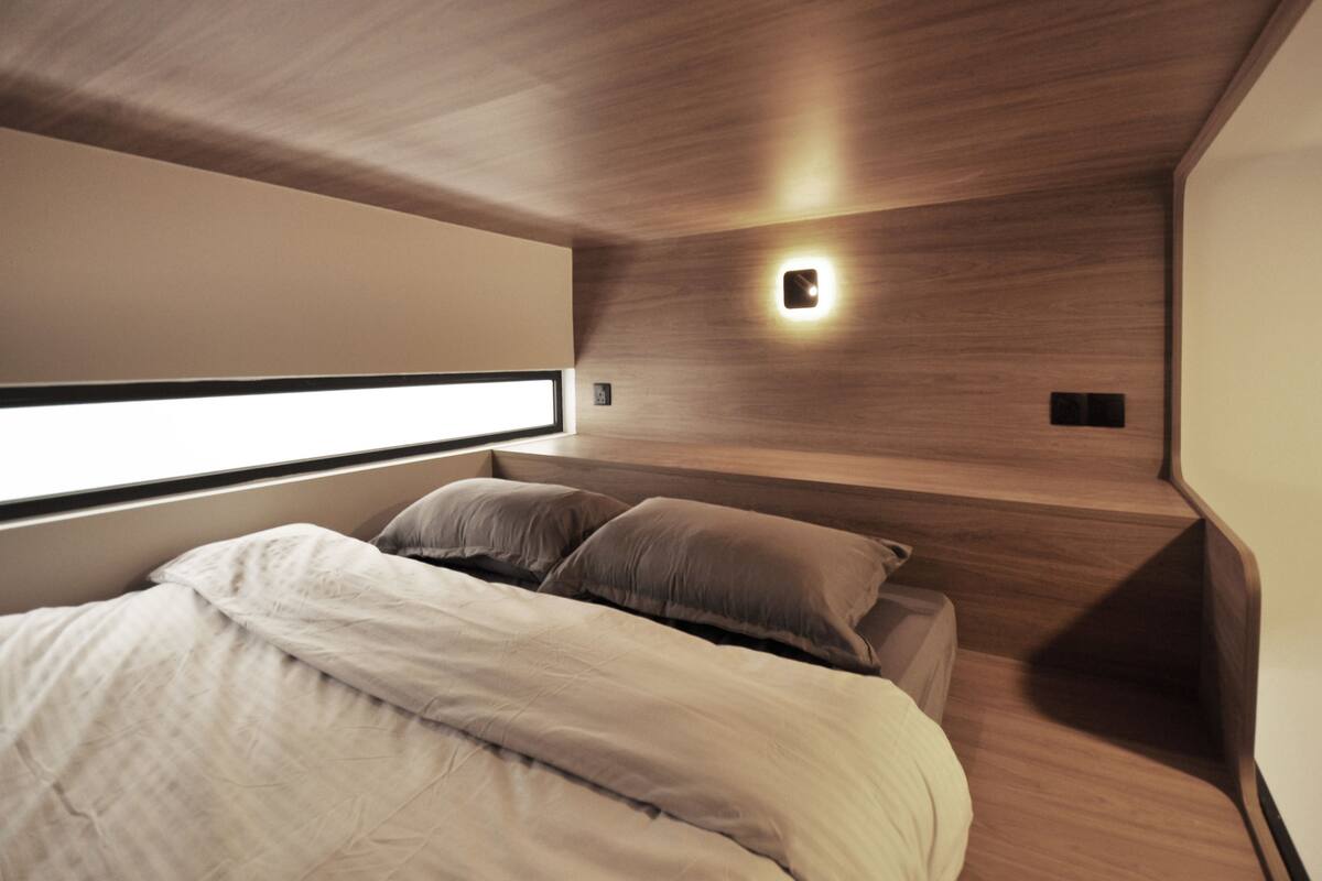 A modern bedroom with a large bed, wooden headboard, and a bedside table.