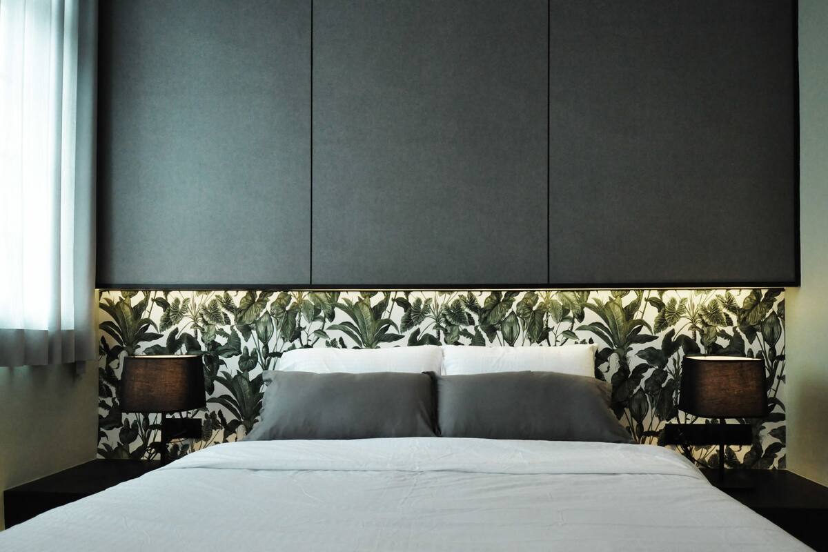 A modern bedroom with a large bed, dark headboard, and two bedside tables with lamps.