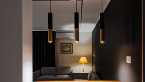 Un salón moderno con una mesa de centro de madera, sofás negros e iluminación colgante.