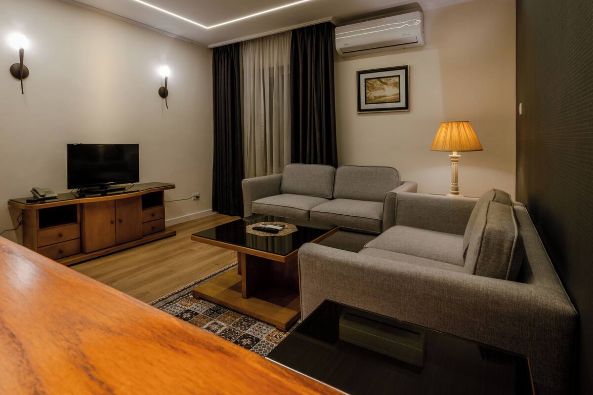 A modern living room with a sofa, TV, and a lamp.