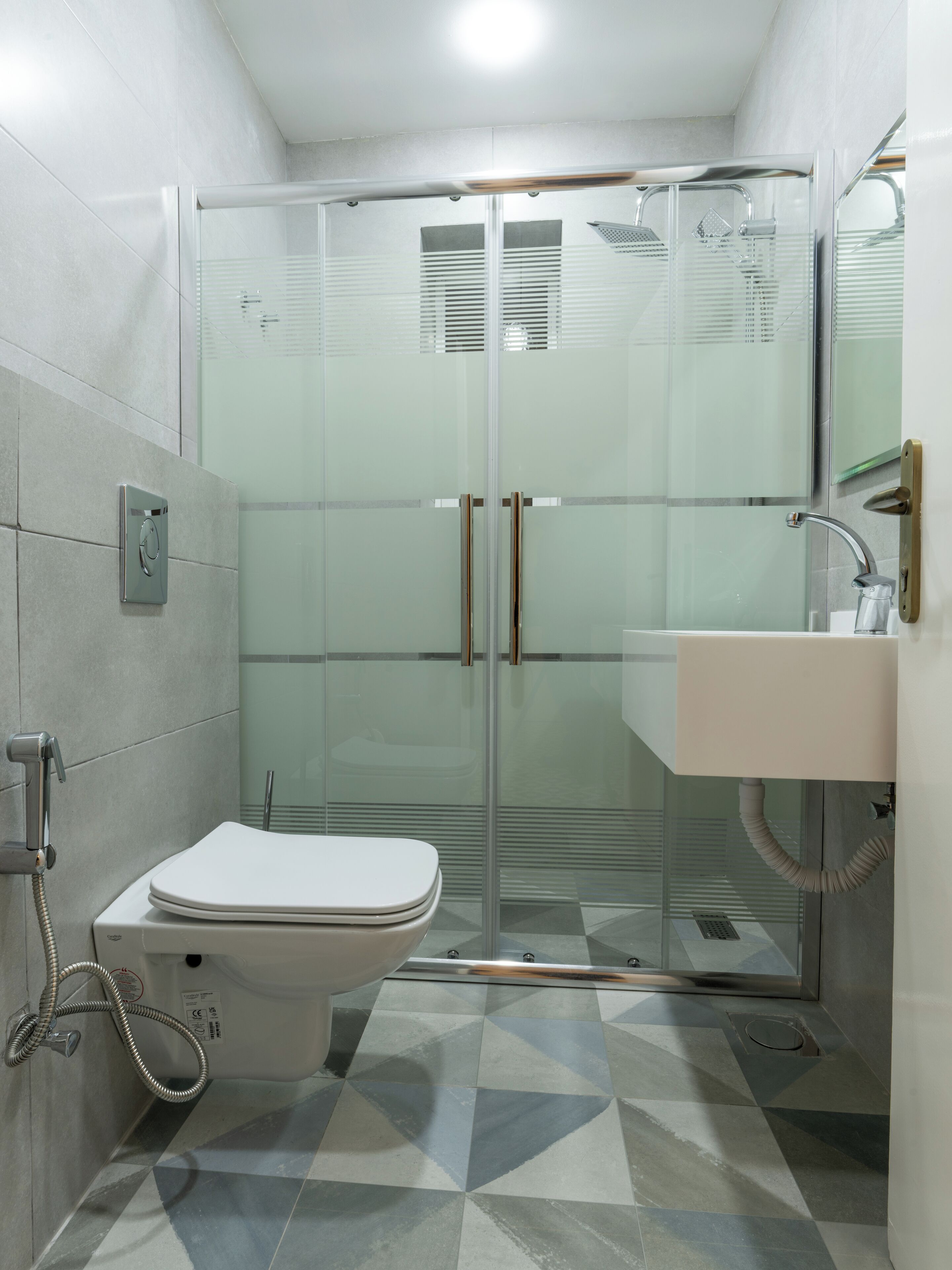 A modern bathroom with a glass-enclosed shower, a toilet, and a sink with a mirror.