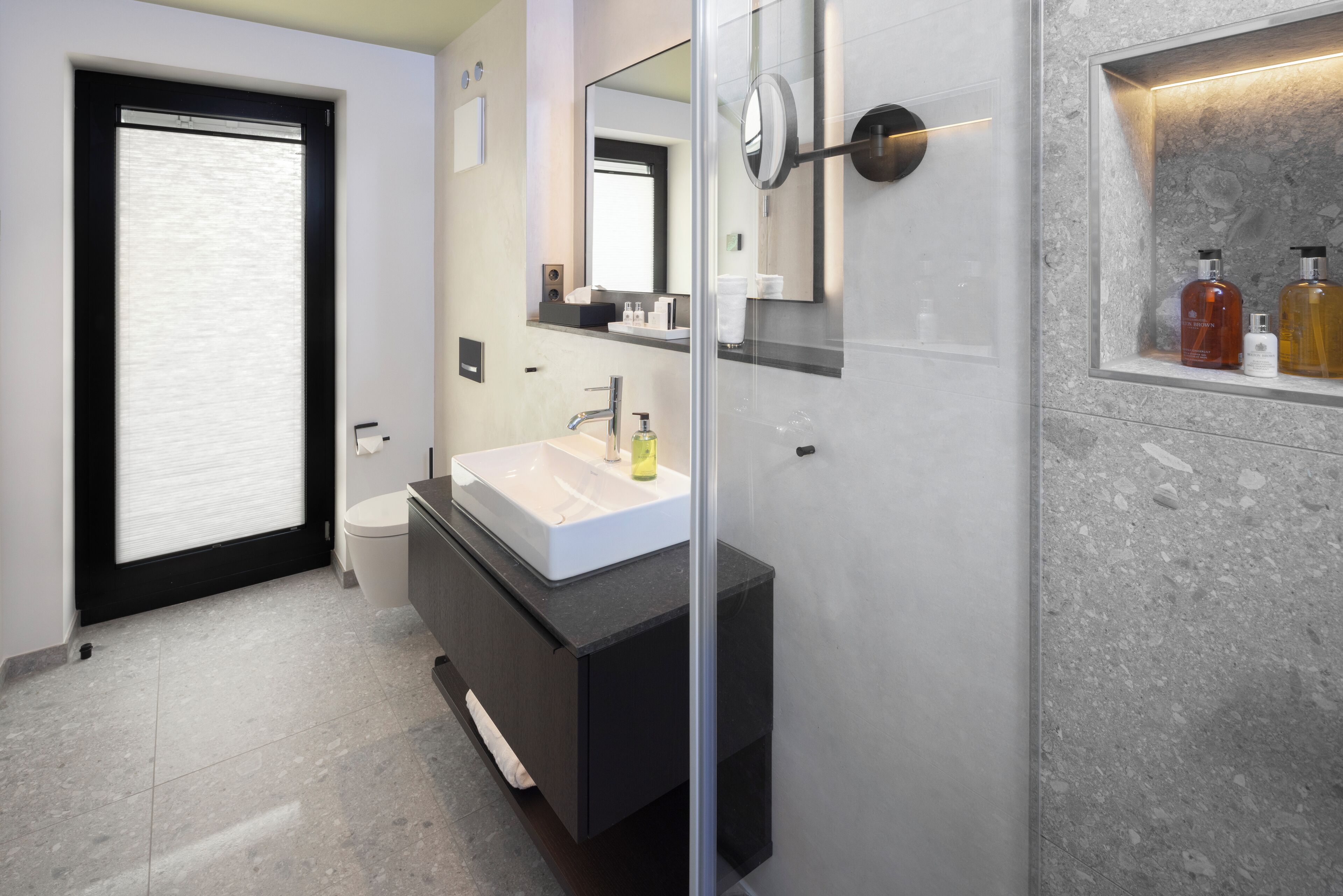 Un baño moderno con un espejo grande, un lavabo blanco y una cabina de ducha de cristal.