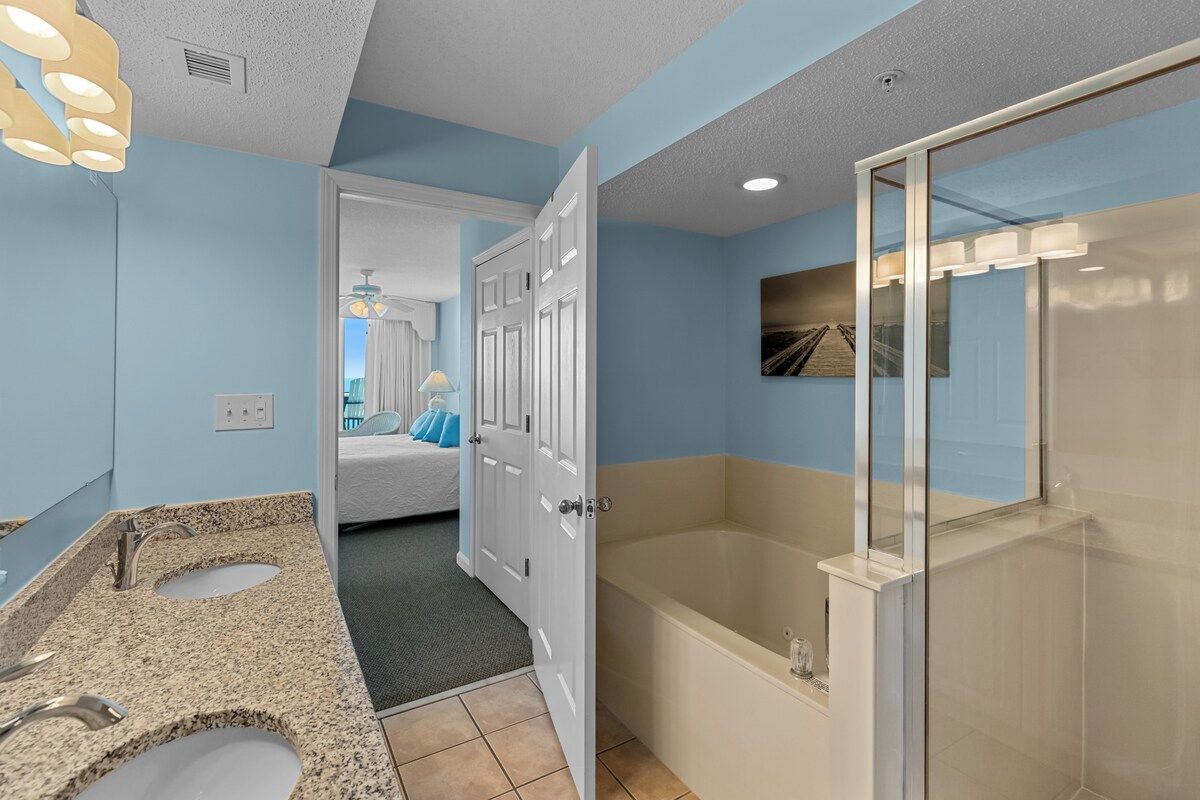 A bathroom with a bathtub, two sinks, and a shower.